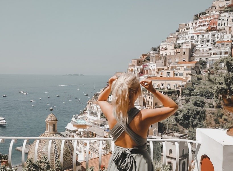 Blonde girl overlooking a railing with Positano houses in the background 