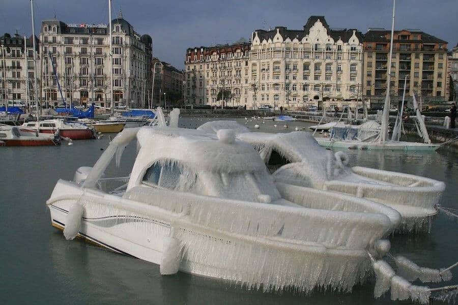 Boat frozen covered in ice and buildings in the distance