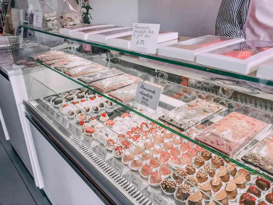 Chocolate covered strawberries and chocolate bars inside a glass display 