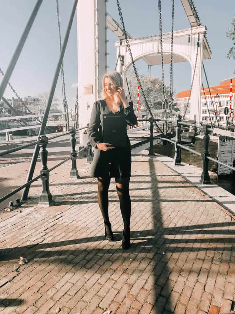 Blonde girl standing infront of a white bridge in Amsterdam