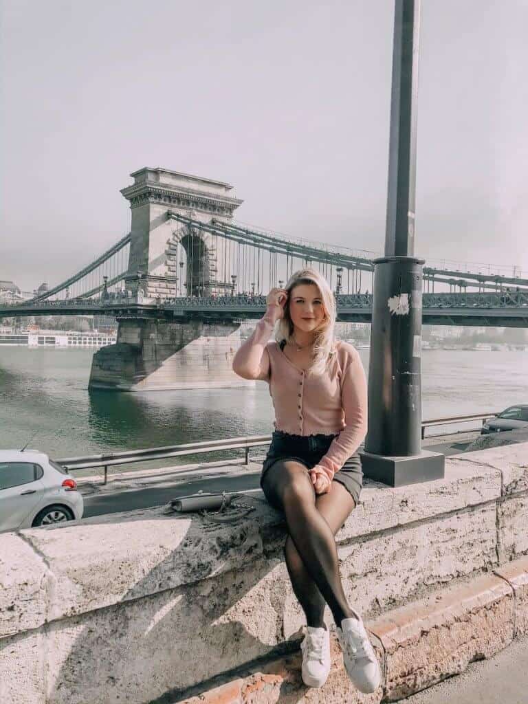 Girl sitting on a ledge with the Szechenyi Chain Bridge in the distance