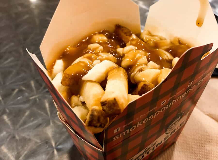 French fries and cheese curds covered in gravy inside a red take out box