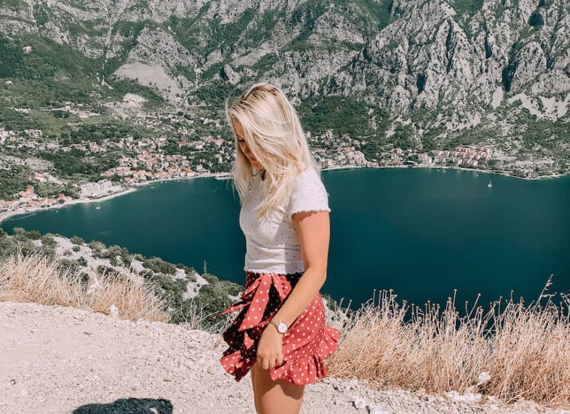 Girl standing in front of mountains and blue water
