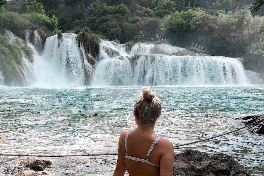 Girl sitting in front of the waterfalls in Krka