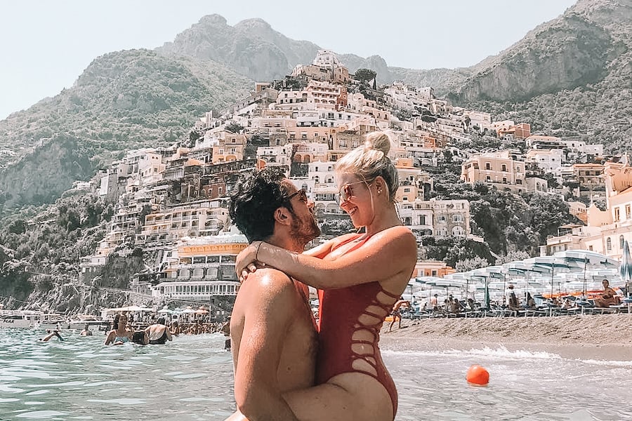 Two people in the water in front of the buildings in Positano