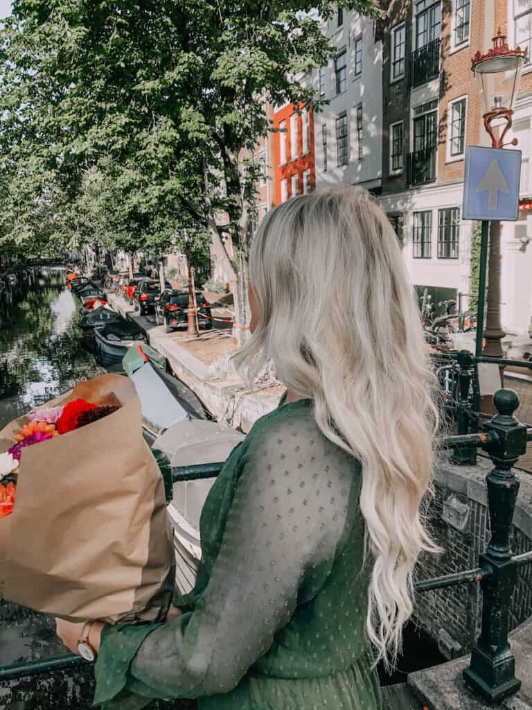 Girl standing on the canal in Amsterdam with a bouquet of flowers