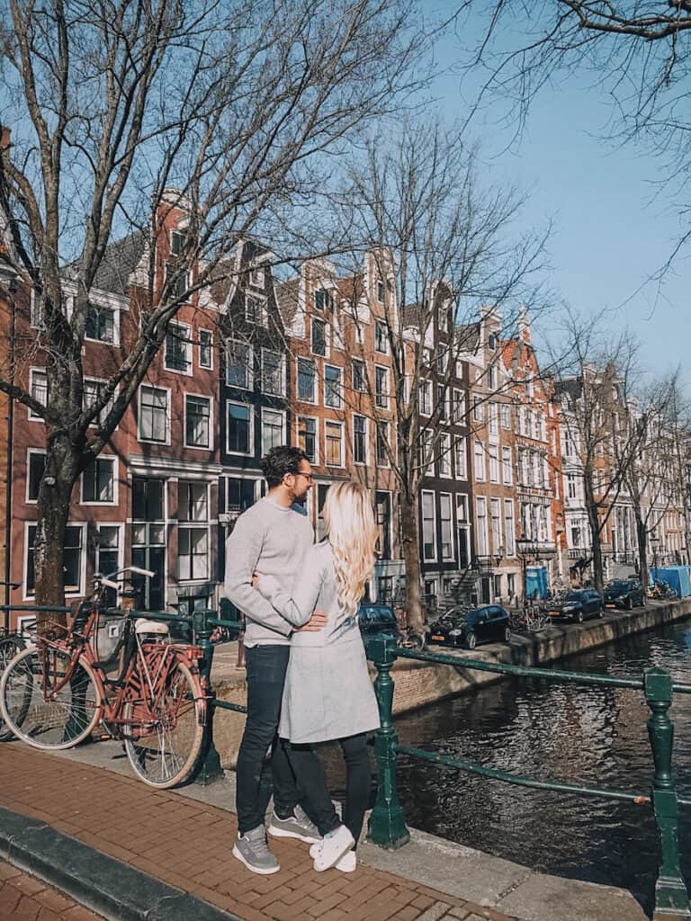 Couple kissing on a bridge in Amsterdam one of the top 10 romantic destinations in Europe