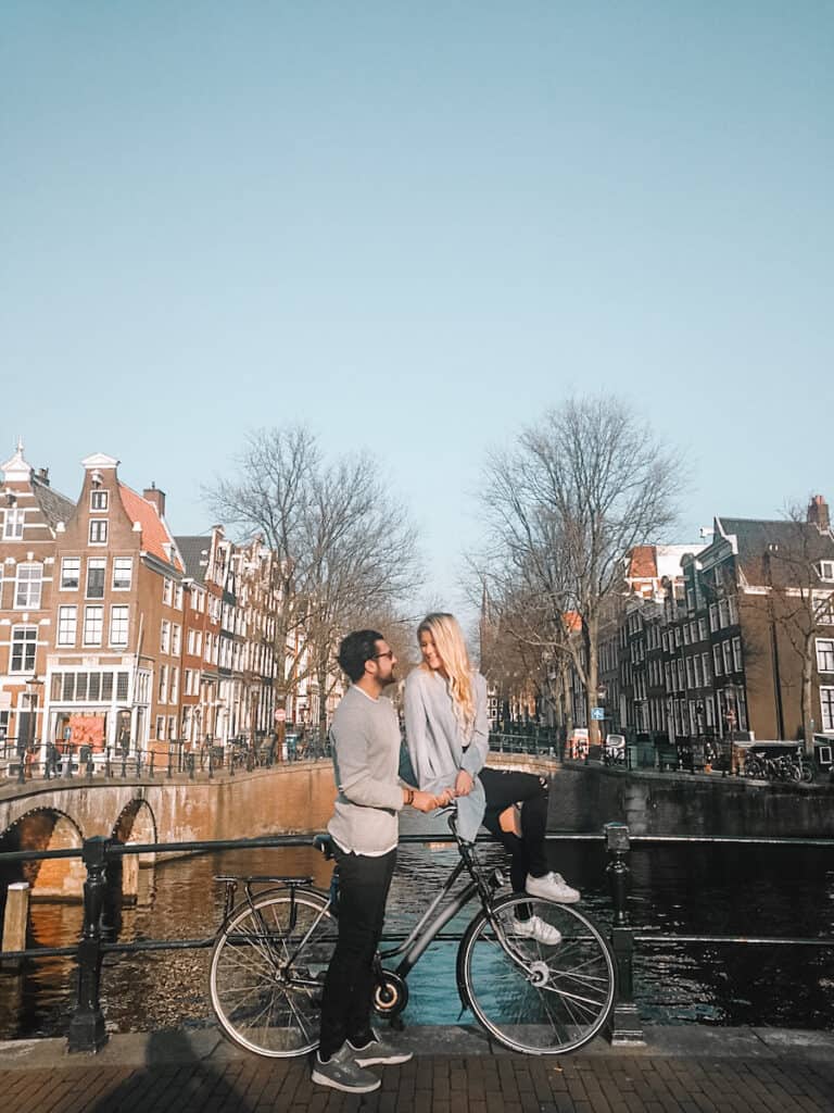 Couple kissing on a bridge in Amsterdam one of the top 10 romantic destinations in Europe