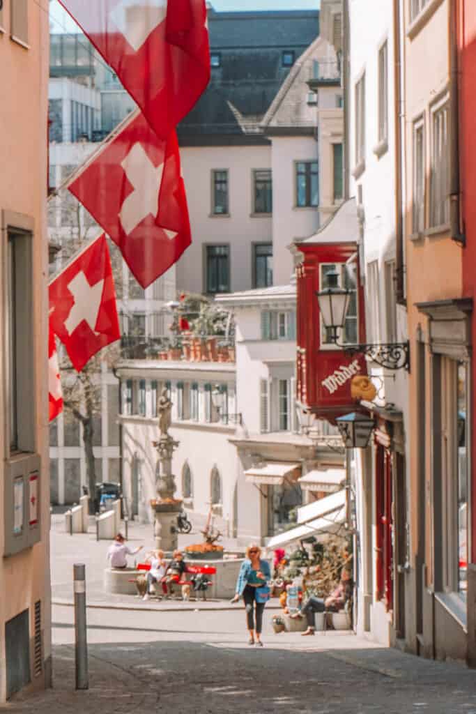 Zurich street view with cobblestone streets and Swiss flags on buildings