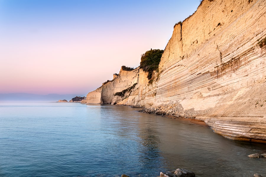 Logas sunset beach with sheer white cliffs in Peroulades village on Corfu Island in Greece. Loggas is famous for scenic viewpoint with beautiful sunset sea view from high rocky limestone cliff