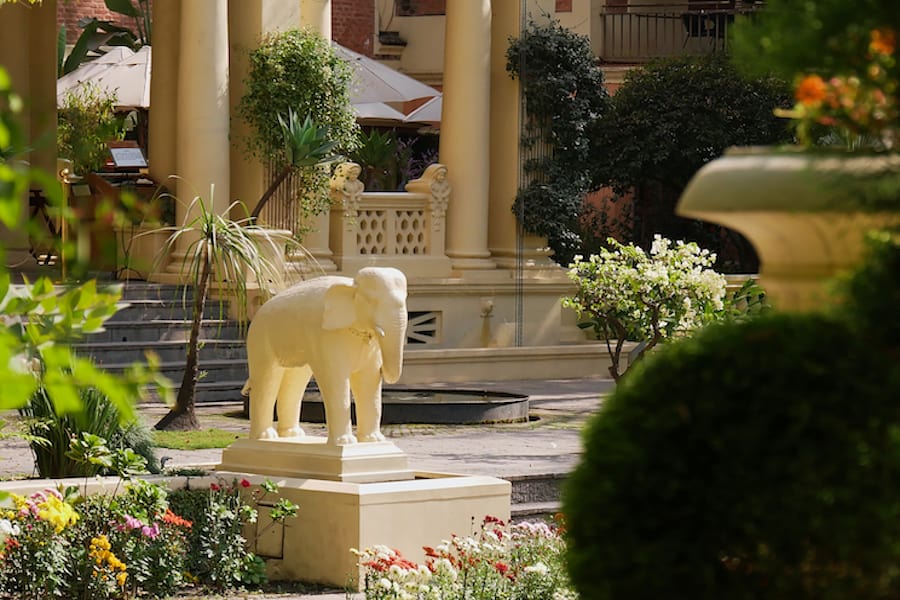 White colored elephant sculpture in the Garden of Dreams (also Garden of Six Seasons) in the center of Kathmandu, Nepal framed by plants. Focus on sculpture.
