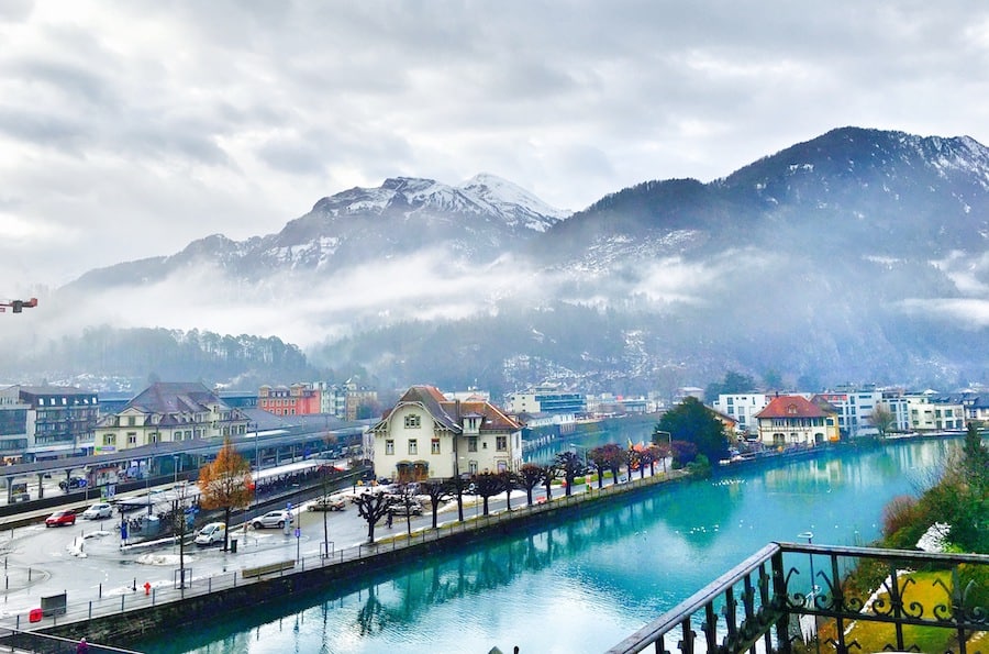 View of beautiful interlaken lake canal,Switzerland from the balcony of hotel in wintertime. Alps mountains covered by snow and colourful of buildings in city covered with foggy as background