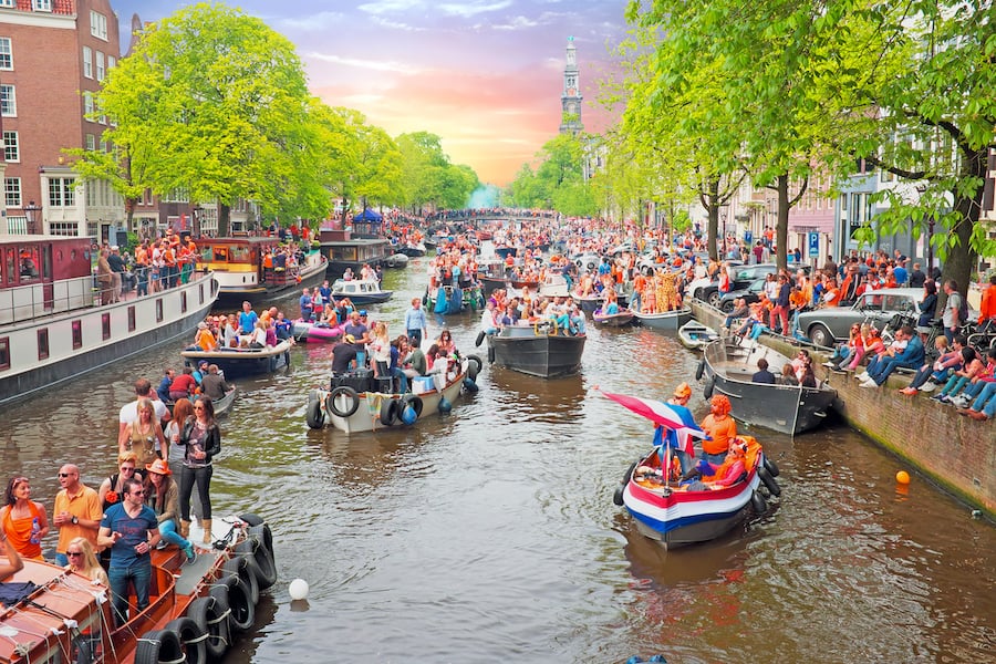 Amsterdam canals full of boats and people in orange during the celebration of kings day on April 26, 2014 in Amsterdam, The Netherlands at sunset