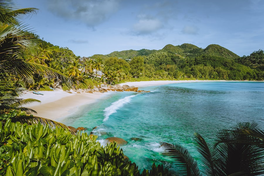 Mahe Island, Seychelles. Holiday vocation on the beautiful exotic Anse intendance tropical beach. Ocean wave rolling towards sandy beach with coconut palm trees.