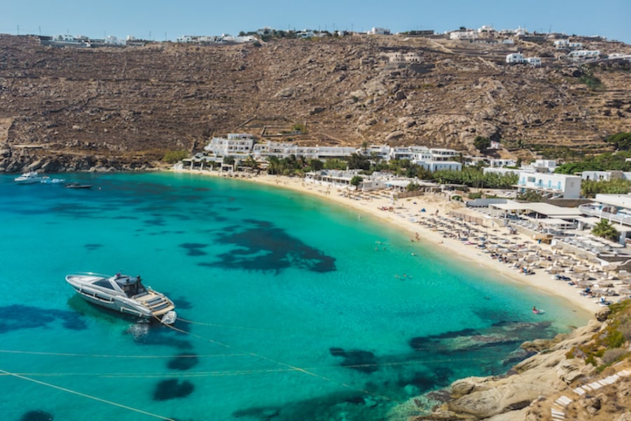 Aerial panoramic view of the famous Psarou bay with iconic Nammos luxury beach bar. Mykonos island, Greece.