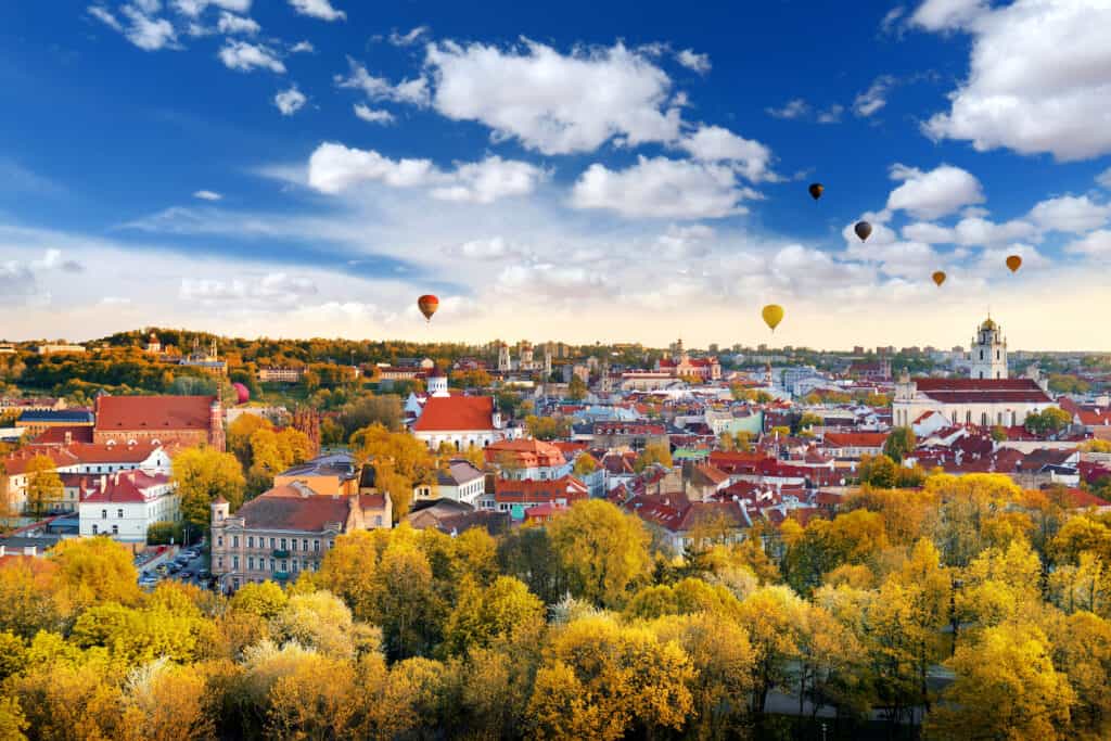 Beautiful autumn panorama of Vilnius old town with colorful hot air balloons in the sky, taken from the Gediminas hill