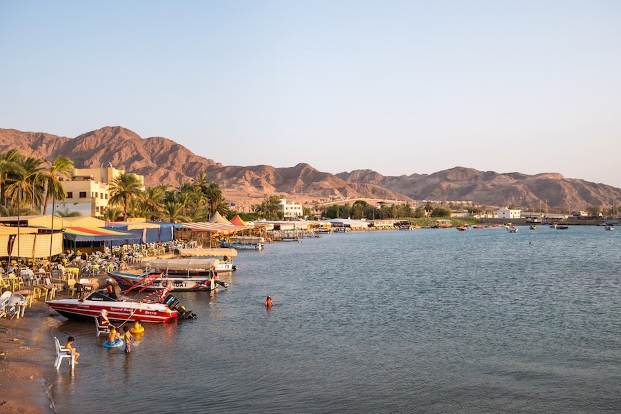 Scenic view at sunset with the beach in Aqaba. Outodoor tables and chairs and boats on the beach.