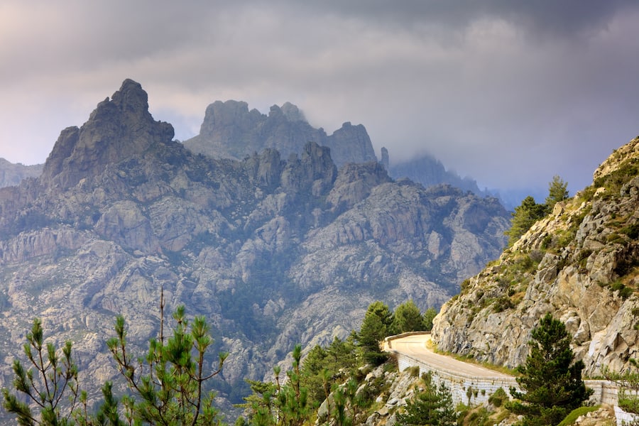 Rough mountains with road and cloudy sky, Col de Bavella, Corsica, France
