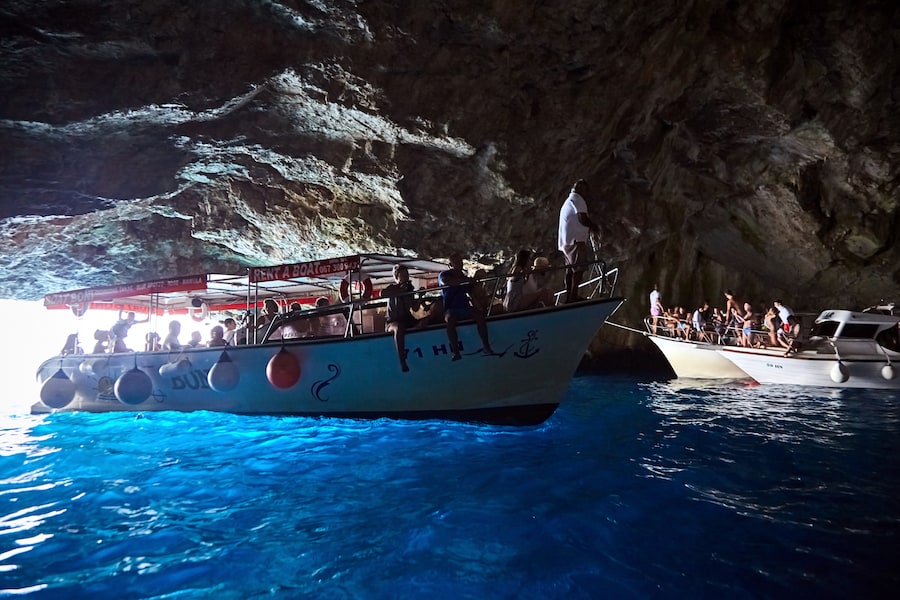 Blue Cave, Lustica Peninsula, Montenegro. The tour boats with people inside cave with water look blue.