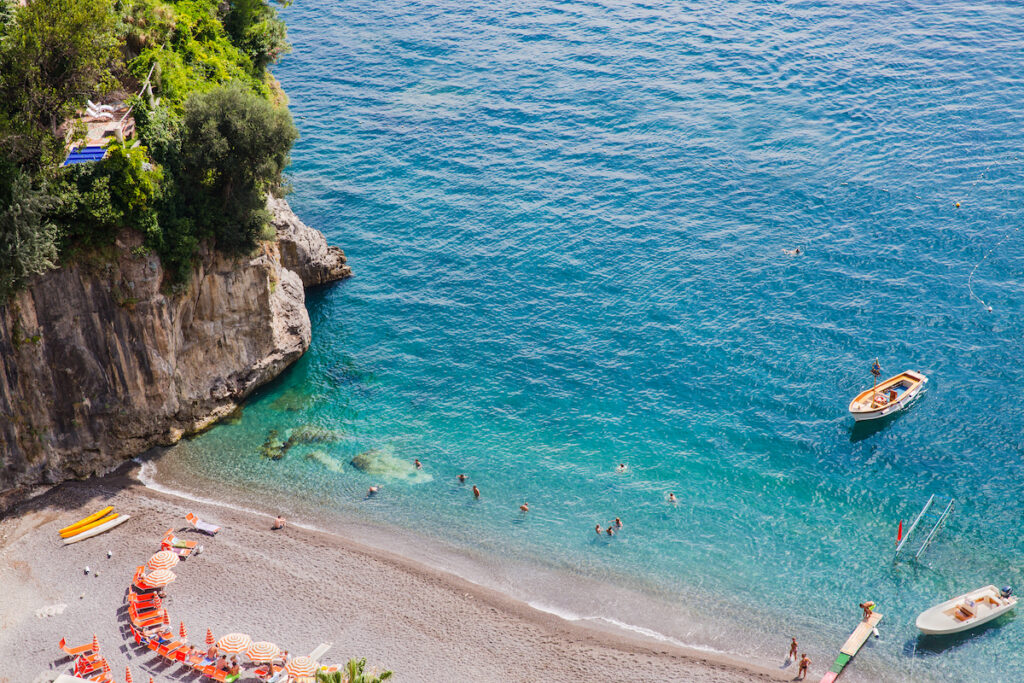 View across to Arienzo beach, near Positano, Amalfi Coast, Italy, where people are swimming and sunbathing