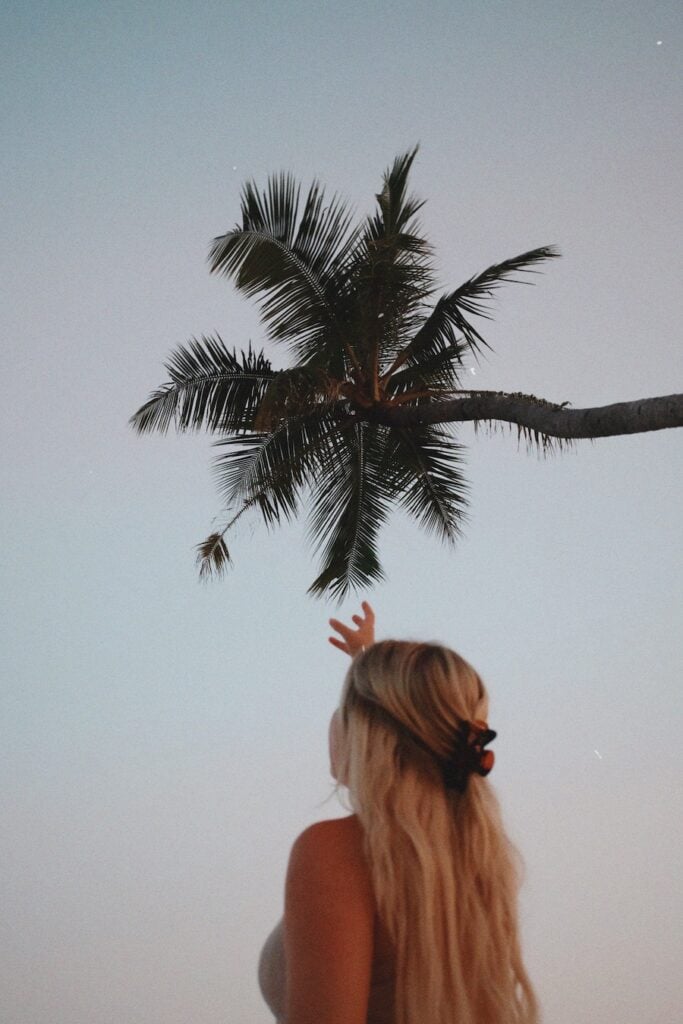 Girl reaching for a palm tree in the Maldives