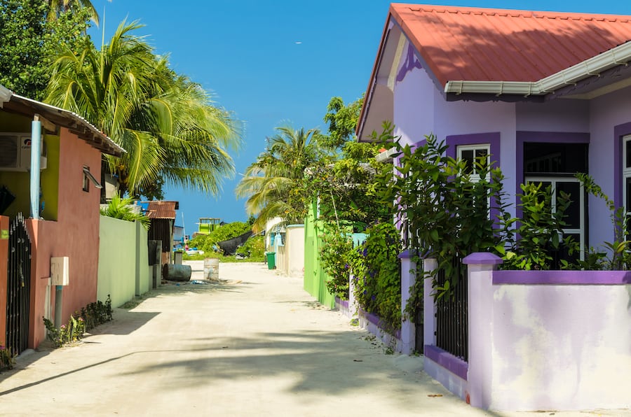 Huraa, Maldives - November 20, 2017: One of the central streets of small tropical island Huraa, overlooking the Indies Ocean with one-story houses and tall palm trees, Kaafu Atoll, Kuda Huraa Island